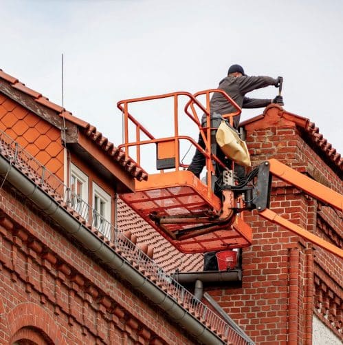Roofing crew applying white elastomeric coating to a flat commercial roof