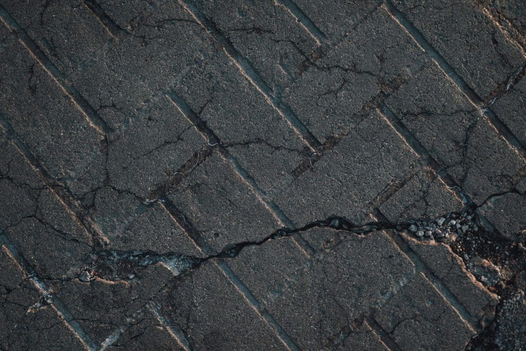 Close-up of cracked and curling asphalt shingles showing granule loss