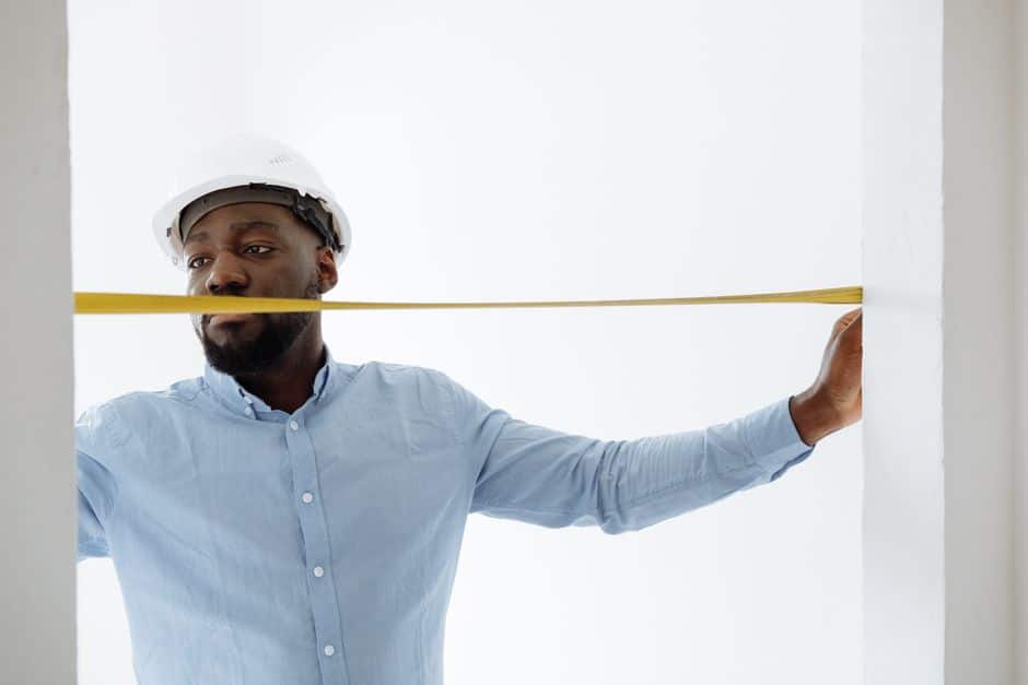 Roofer measuring a home's roof to prepare an estimate